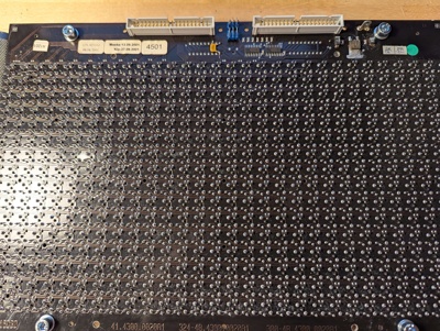 Back of the flipdot matrix, showing the matrix itself (duh), two IDC connectors, a blade terminal, two shift registers, solder joints for driver ICs on the other side of the PCB, and a voltage regulator. A sticker indicates that the module was likely assembled in September 2001.
