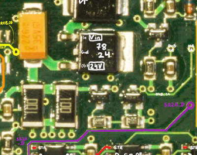 A closeup photo of a PCB, with a 7824 regulator labeled, surrounded by some components, notably two 2512 SMD 10 ohm resistors, two tiny transistors, and a bunch of other small parts.